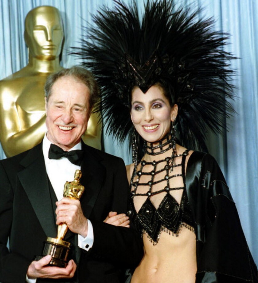 Cher, seen in one of Bob Mackie’s most flamboyant creations, at the 1986 Academy Awards, where she presented Don Ameche (left) with the best supporting actor Oscar. | Lennox McClenndon/AP Photo