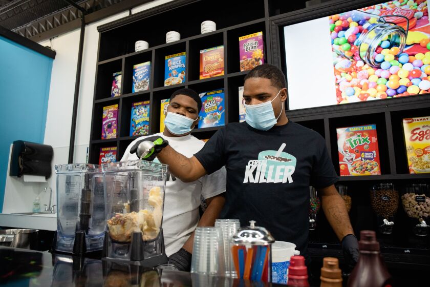 Kameron Cole, 15 (left), and his brother Keenan Cole, 20, make milkshakes at Munchiez in Beverly. The young men are co-owners of the shop along with their mom.