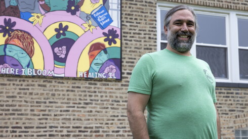 Nicholas Pesa, art teacher at Chicago International Charter School Prairie stands in front of the new mural on side of the Roseland "cop house," a new spot for neighborhood and youth programming.