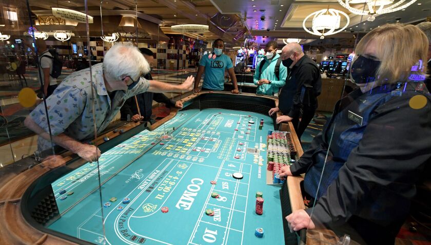 Guests play craps June 4 on a table with plexiglass safety shields at Bellagio Resort & Casino on the Las Vegas Strip after the property opened for the first time since being closed on March 17 because of the coronavirus.