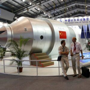 Visitors sit beside a model of China’s Tiangong-1 space station in 2010. | AP file photo