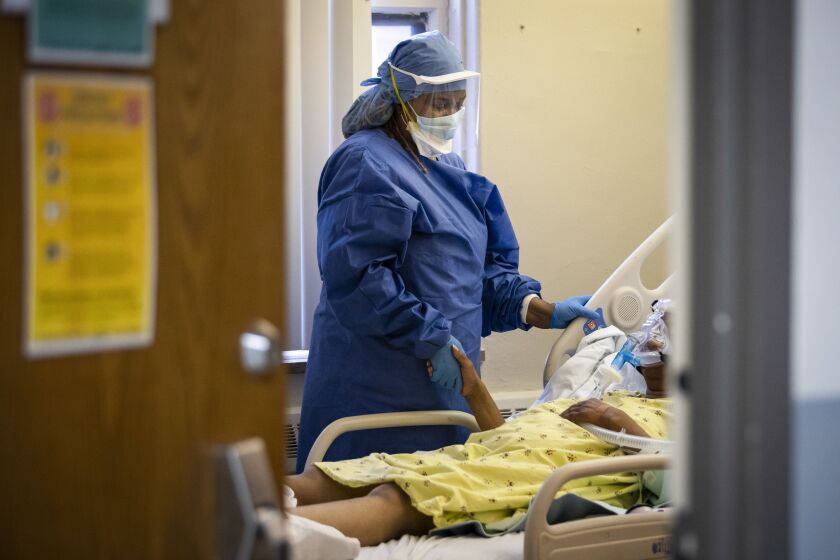 Nurse Jeanette Averett comforts a 56-year-old woman suffering from COVID-19 who was struggling with anxiety because of her non-invasive ventilator at Roseland Community Hospital on the Far South Side, Tuesday afternoon, April 28, 2020. During the standard 12-hour day shift that day, nurses and doctors responded to five code blues and three patients died from complications from COVID-19.