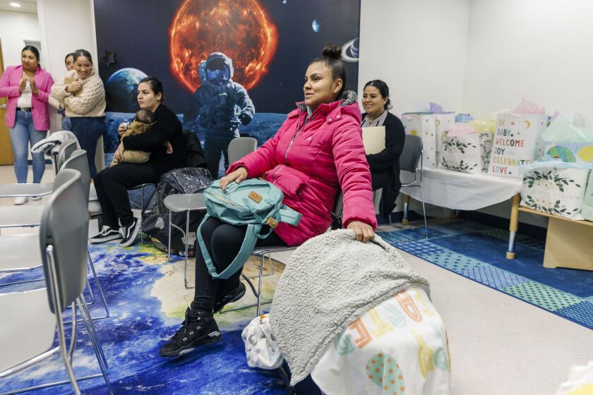 Lizzet Gonzalez rocks her son, Ismael, as she listens to a presentation during a communal baby shower held at the Pilsen offices of community organization El Valor. 