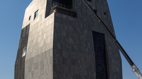 Construction vehicles near the Obama Presidential Center's 225-foot museum tower, clad in light-colored New Hampshire granite.