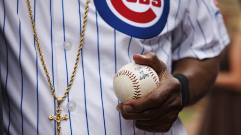 Mr. T wears a gold crucifix necklace and holds a baseball as he warms up for his ceremonial pitch.