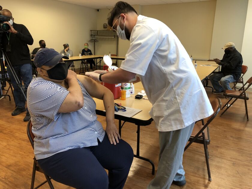 Sylvia Green rolls up her sleeve for Walgreen’s pharmacy student Ghassan Ayyad at the Victor Walchirk Apartments in Evanston as part of Cook County’s effort to inoculate public housing residents against COVID-19.