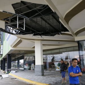 Residents stand beside a damaged portion of a mall due to strong winds from Typhoon Mangkhut as it barreled across Tuguegarao city in Cagayan province, northeastern Philippines on Saturday, Sept. 15, 2018. The typhoon slammed into the Philippines northeas
