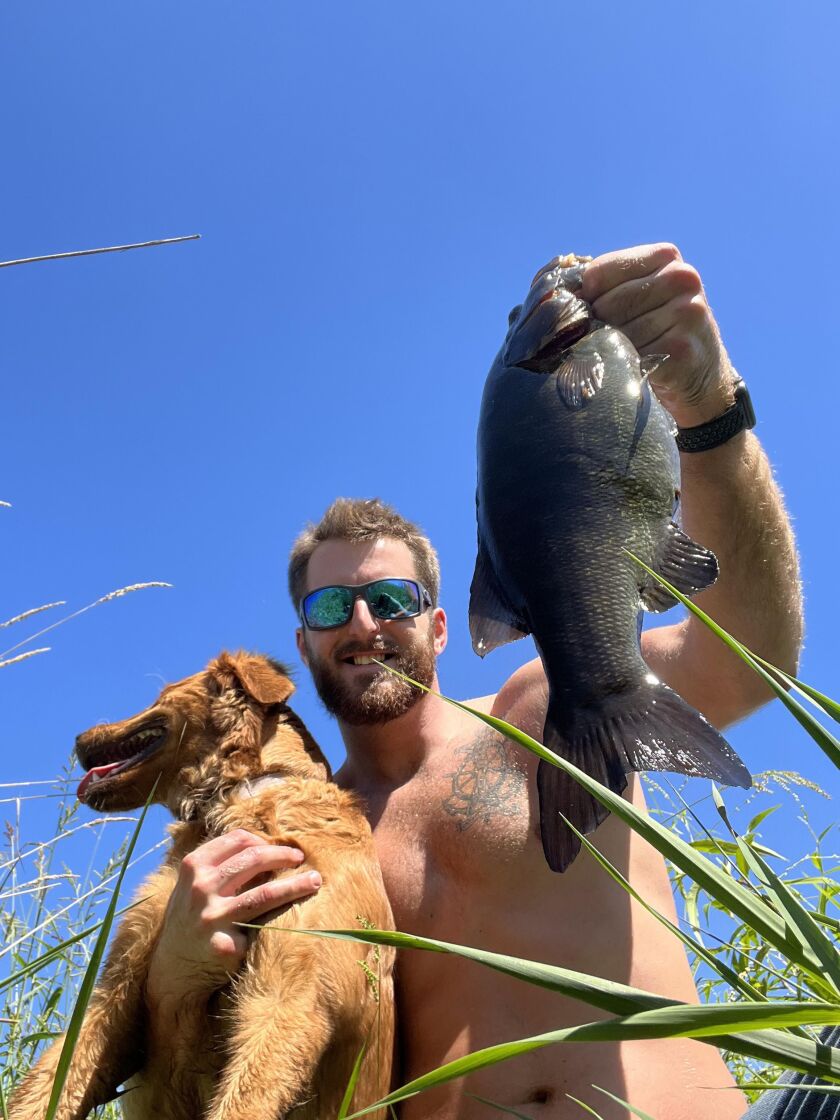 Capt. A.J. Cwiok and his girlfriend’s golden retriever Rory enjoy a smallmouth bass from the DuPage River. Provided photo