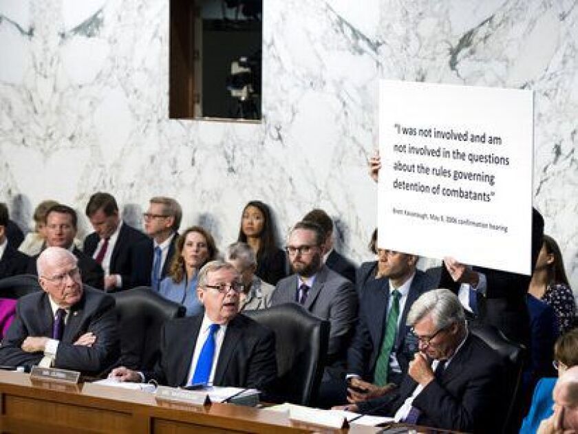 A staffer holds up a poster as Sen. Richard Durbin, D-Ill., makes his opening statement during the confirmation hearing of Brett Kavanaugh to be Associate Justice of the Supreme Court in the Senate Judiciary Committee on Tuesday morning, Sept. 4, 2018. |