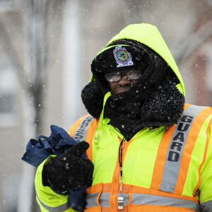 A crossing guard stands on a corner on the Near West Side as snow falls on the Chicago area during the morning commute, Wednesday, Feb. 26, 2020.