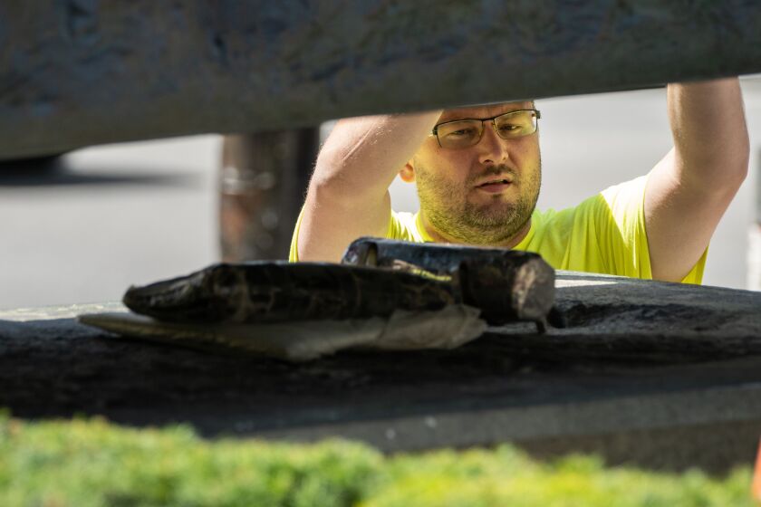 A crew member from Conservation of Sculpture and Objects Studio looks at a time capsule placed on the base where one of the Art Institute of Chicago’s famous lion sculptures was being reinstalled after being removed for a cleaning, Tuesday morning, July 19, 2022.