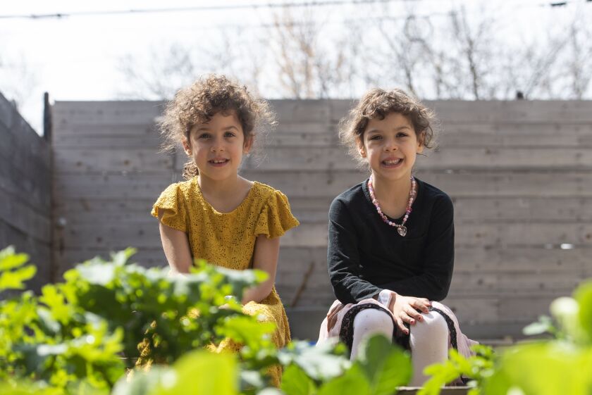Hilde (left) and Elsie Shapiro-Braddy, 6 year old twins, sit in their garden where they’ve been spending their time during the coronavirus pandemic, Tuesday, April 28, 2020.