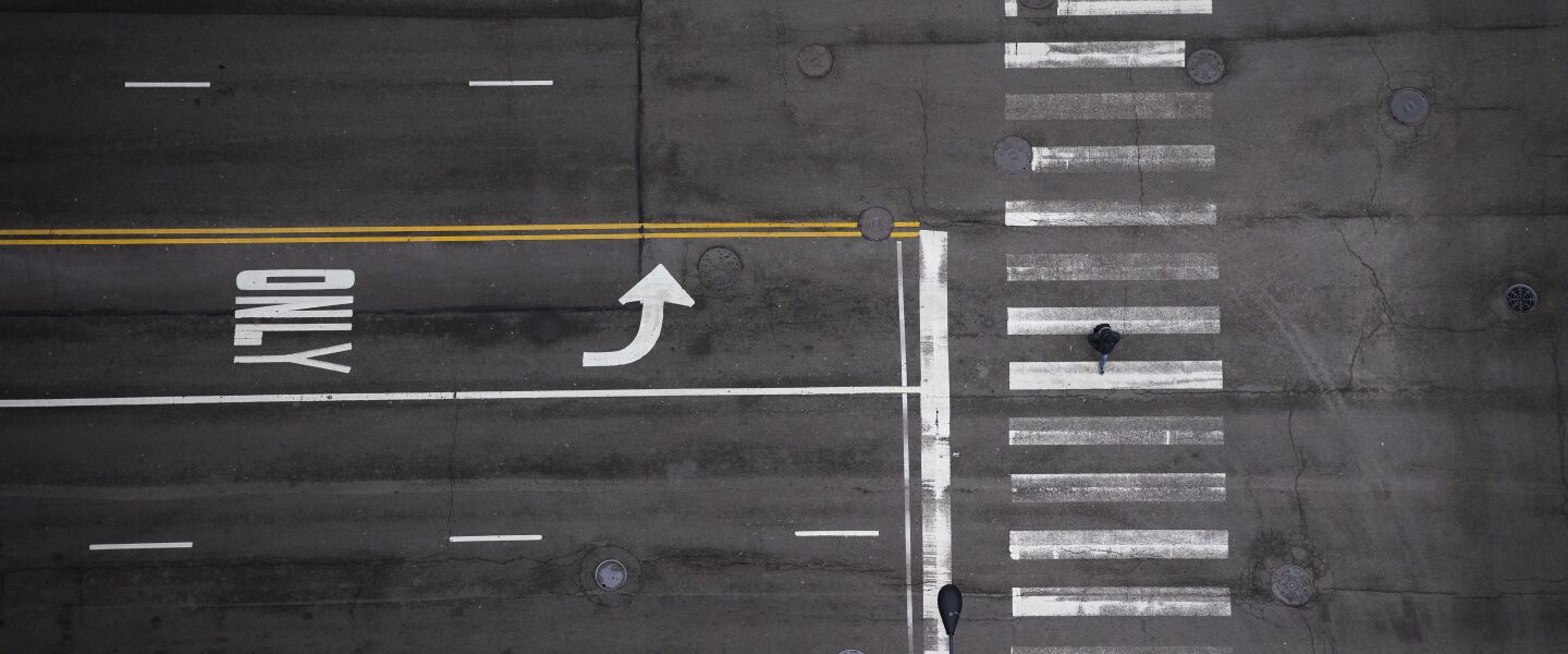 A pedestrian walks alone in the crosswalk on North LaSalle Street at West Randolph Street in the Loop, as seen from the roof of City Hall during the Wednesday morning commute, April 1, 2020.