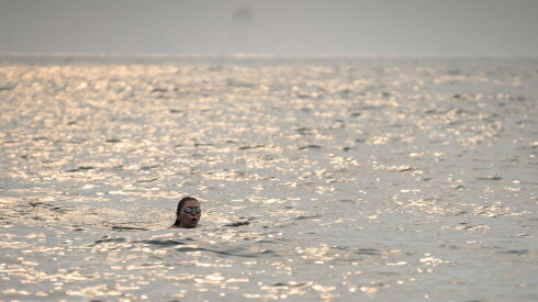 On a hazy morning, a person swims in Lake Michigan near Montrose Point Bird Sanctuary as smoke from the Canadian wildfires pollutes the city.