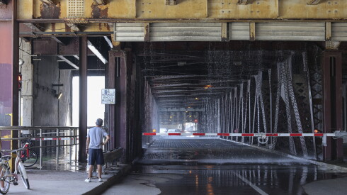 Personas esperan en el Lakefront Trail mientras el Departamento de Bomberos de Chicago rocía agua sobre el puente DuSable Lake Shore Drive para enfriarlo el miércoles.