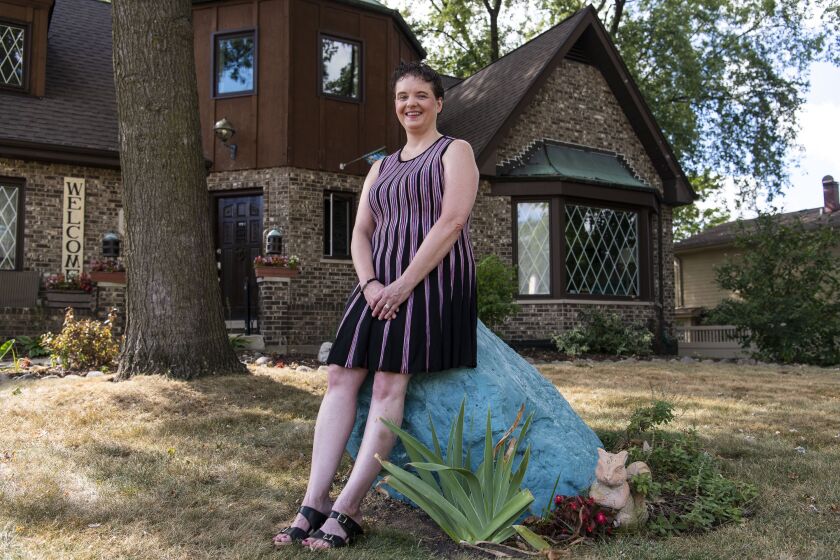Jenn Szwajkowski sits atop a rock painted teal by her husband Ron)in her front yard in the south suburbs. Teal is the signature color of the ovarian cancer awareness movement.