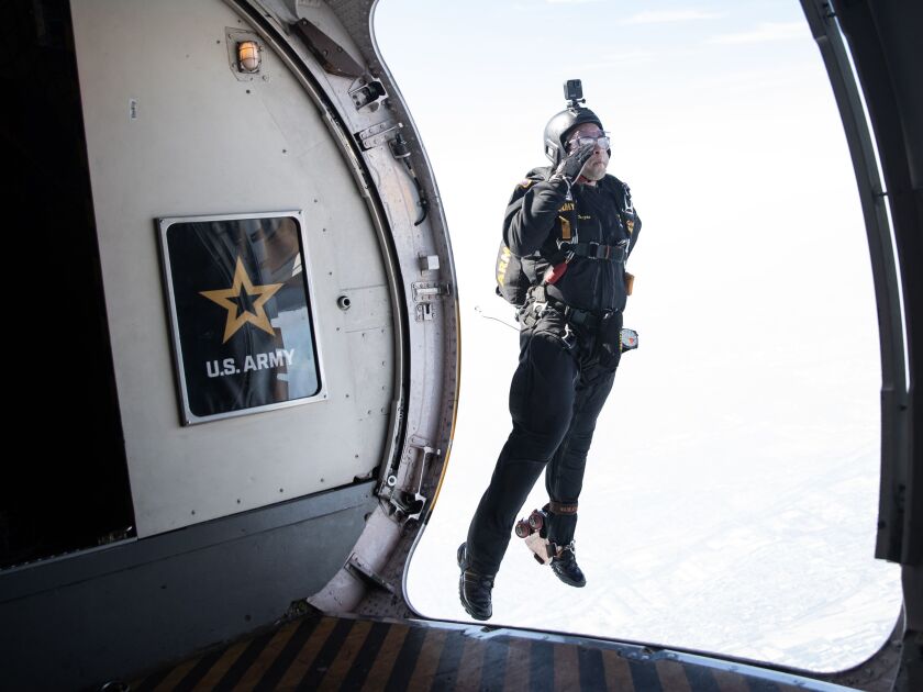 Staff Sgt. Nickolas Orzoco salutes while jumping out of the U.S. Army Golden Knight’s C-147A plane Friday during a practice jump before the 2023 Chicago Air and Water Show.