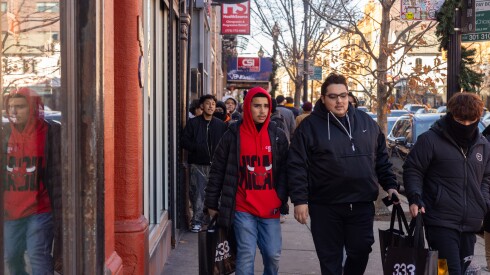 Black Friday shoppers leave Half Evil's store in Wicker Park, with their new purchases in tow as other shoppers behind them wait in line to enter the Chicago streetwear brand's shop.
