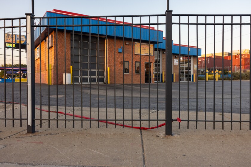 Red crime scene tape lies on the ground attached to the gate at Big Rig Oil Pros in Brighton Park, Saturday, Oct. 4, 2025. Earlier in the day, a woman drove to the auto shop seeking help after being shot by federal agents nearby. | Candace Dane Chambers/Sun-Times.