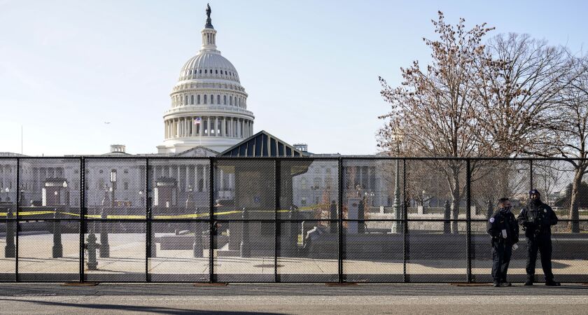 Capitol police officers stand outside of fencing that was installed around the exterior of the Capitol grounds on Thursday.