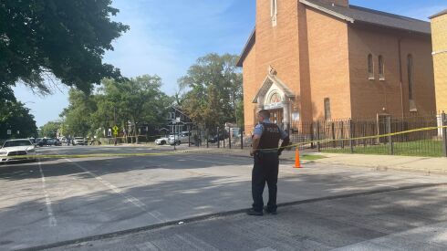 A police officer on Saturday stands outside Universal Community Missionary Baptist Church in Roseland where three people were wounded when a gunman firing from a car targeted a group of people attending a funeral service.