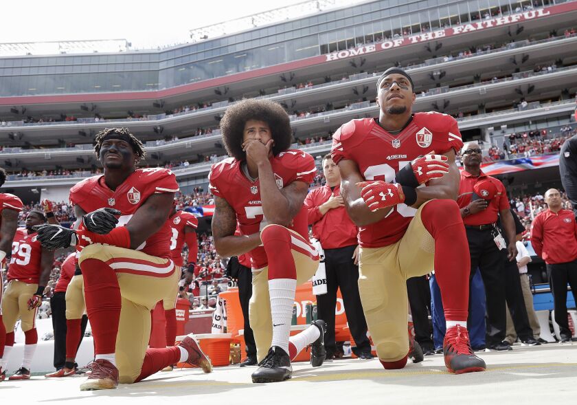 San Francisco 49ers outside linebacker Eli Harold (left), then-quarterback Colin Kaepernick and safety Eric Reid kneel during the national anthem before an NFL football game against the Dallas Cowboys in October 2016. | Marcio Jose Sanchez/AP photo