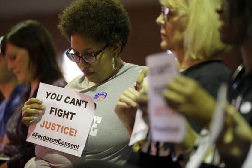 Alicia Street holds a sign as she sits in the audience during a meeting of the Ferguson City Council on Tuesday. | Jeff Roberson/AP
