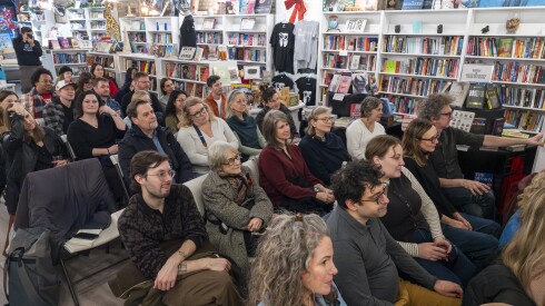 People sit in rows in chairs in a bookstore.