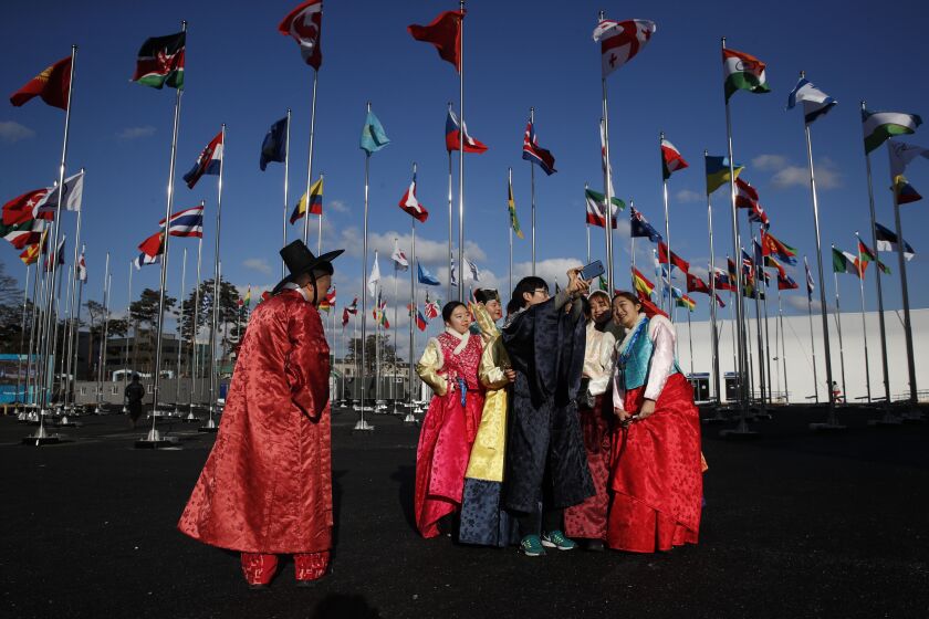 A group of volunteers wearing handbook, Korean traditional dress, take selfies at the Olympic Village prior to the 2018 Winter Olympics in Gangneung, South Korea, on Thursday. | AP photo