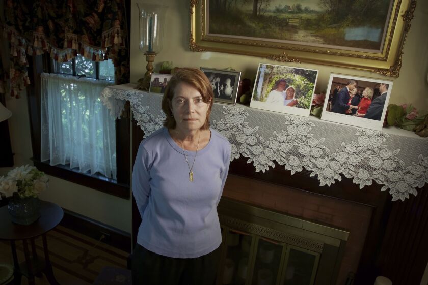 Margot Eckert stands by a display of pictures of her brother-in-law Sean Rooney and sister Beverly Eckert at her home in Springfield, Mass. Rooney was killed on 9/11 while working in his office in the South Tower. His wife Beverly Eckert died in a plane crash in 2009.