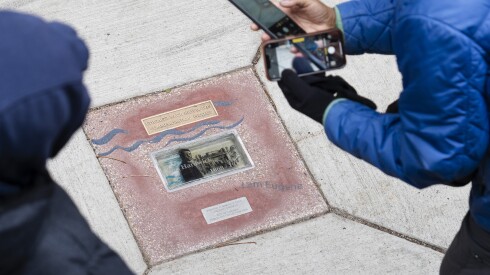 People look at the memorial for Paul Hardwick, a Black waiter at the Palmer House Hotel who was fatally shot while being chased by a mob of white men, during a walking tour organized by the Chicago Race Riot of 1919 Commemoration Project at the intersection of East Adams Street and South Wabash Avenue in the Loop, Saturday, Nov. 8, 2025. The memorials were placed in different areas in the Loop to mark the approximate location where people were killed during the riots. The riots began after police failed to arrest a white man, who threw a stone at Eugene Williams, a Black kid, when he was swimming in Lake Michigan and led to his drowning.