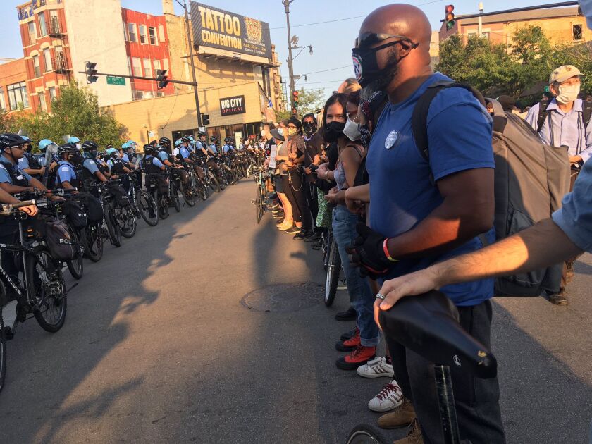 Demonstrators and police line up at 18th and Loomis streets on Saturday during a march in support of the family of Miguel Vega, who was fatally shot by police earlier this week in the neighborhood.