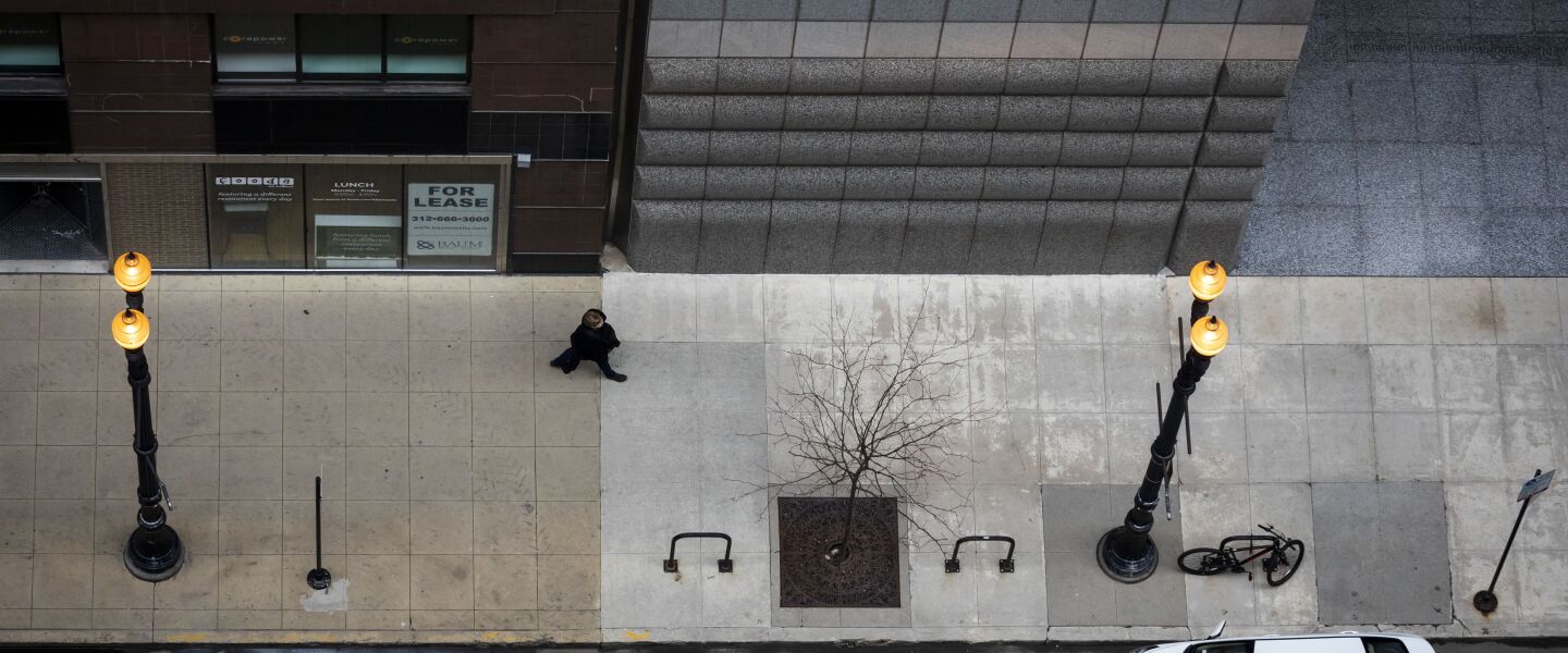A pedestrian walks alone on North LaSalle Street near West Randolph Street in the Loop, as seen from the roof of City Hall during what should have been the Wednesday morning commute, April 1, 2020.