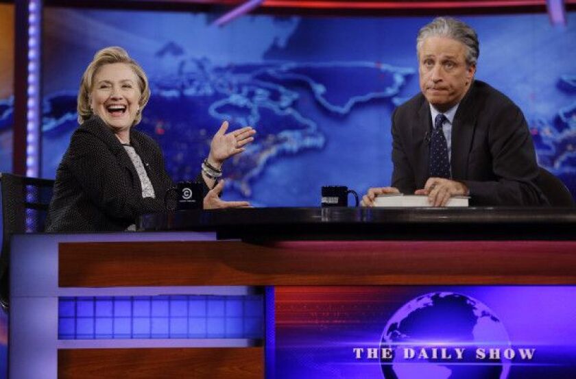 In this July 15, 2014 file photo, former U.S. Secretary of State Hillary Rodham Clinton reacts to host Jon Stewart during a taping of “The Daily Show with Jon Stewart,” in New York. After more than 16 years and nearly 2,600 telecasts, Stewart will end his