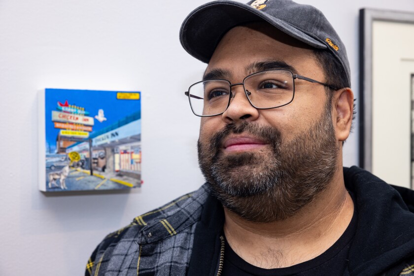 Artist Danny Torres stands alongside his painting, "Chicken Inn (A Song for my Brother)," featured in "Black Swan Elegies: An Artists’ Tribute to Tony Fitzpatrick," on view at the West Town Chamber of Commerce, on Saturday, Dec. 19, 2025.