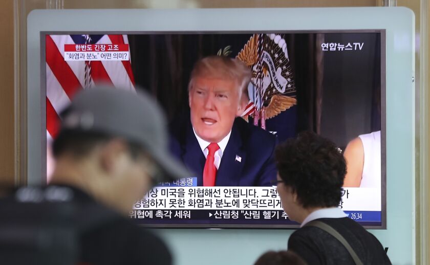 People walk by a TV screen showing a local news program reporting with an image of U.S. President Donald Trump at the Seoul Train Station in Seoul, South Korea on Wednesday. | Lee Jin-man/AP