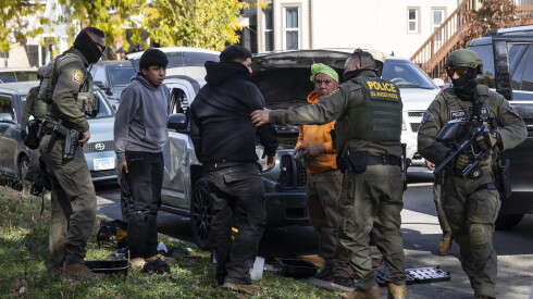 Federal immigration enforcement agents stop a group of people to question their citizenship on Chicago's Southwest Side on Nov. 6, 2025.