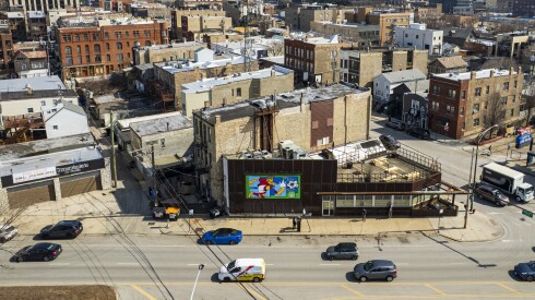 An aerial photo shows a mural of a soccer player on the wall of a building near a busy intersection.