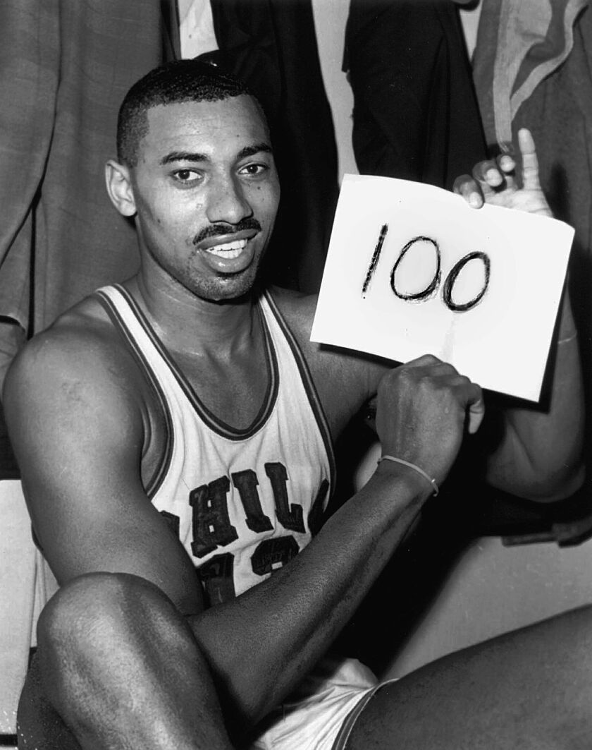 In this March 2, 1962, file photo, Wilt Chamberlain of the Philadelphia Warriors holds a sign reading “100” in the dressing room in Hershey, Pa., after he scored 100 points as the Warriors defeated the New York Knickerbockers 169-147. Recordings reaching