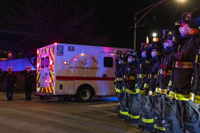 Chicago firefighters salute as the procession carrying the remains of retired firefighter Dwain Williams arrives at the Cook County Medical Examiners Office, after Williams was shot and killed in the 2400 block of West 118th Street in the Morgan Park Neighborhood, Thursday, Dec. 3, 2020.