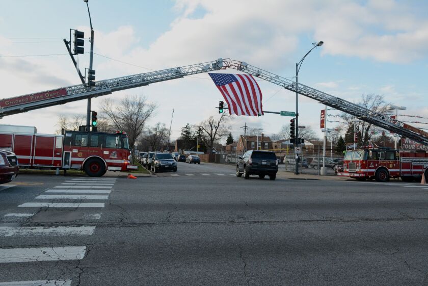 A U.S. flag is draped from two fire engine ladders outside St. Rita. | Brian Jackson/For the Sun-Times