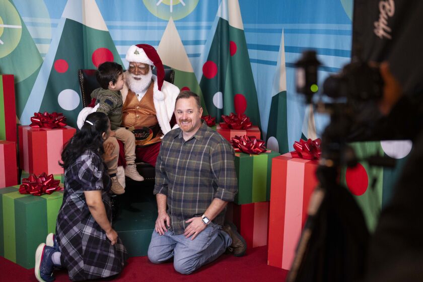Santa Larry, the Mall of America’s first Black Santa, takes pictures with Angela Massey, Jake Driskell and their son Lawrence Driskell after a tree lighting ceremony at the Museum of Science and Industry, Saturday, Nov. 18, 2023.