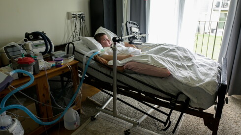Syrian refugee Omar, 19, in a hospital bed his family's living room.