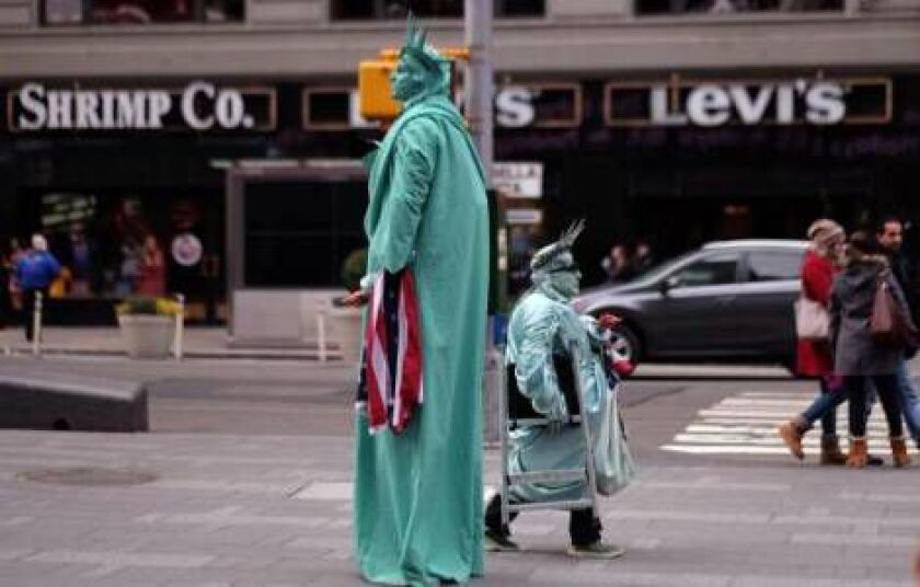Two men dressed as the Statue of Liberty look for tourists to pose with them for pictures in exchange for donations in New York’s Times Square on January 20. 2015. JEWEL SAMAD/AFP/Getty Images