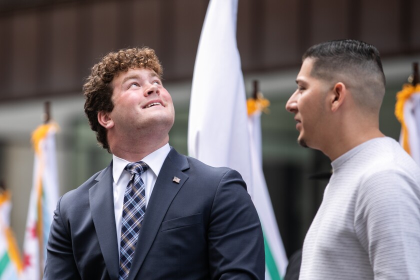 Дрю Даффи, который разработал новый флаг округа Кук, смотрит на старый флаг, а его наставник Мартин Бурсиага стоит рядом с ним во время открытия нового флага на Дейли Плаза в Лупе, суббота, 24 сентября 2022 года. Новый флаг округа Кук был Разработан учеником старшей школы Дрю Даффи под руководством своего наставника Мартина Бурсиаги. | Пэт Набонг / Sun-Times