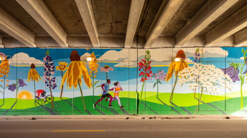 An underpass on the Far Northwest Side shows giant flowers native to Illinois, and runners passing by them.