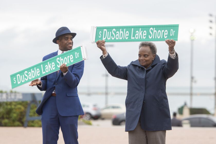 Ald. David Moore and Mayor Lori Lightfoot hoist DuSable Lake Shore Drive street signs on Thursday, Oct. 21, 2021 at Buckingham Fountain during the official unveiling of signs that will be installed along the renamed Jean-Baptiste Pointe DuSable Lake Shore Drive.