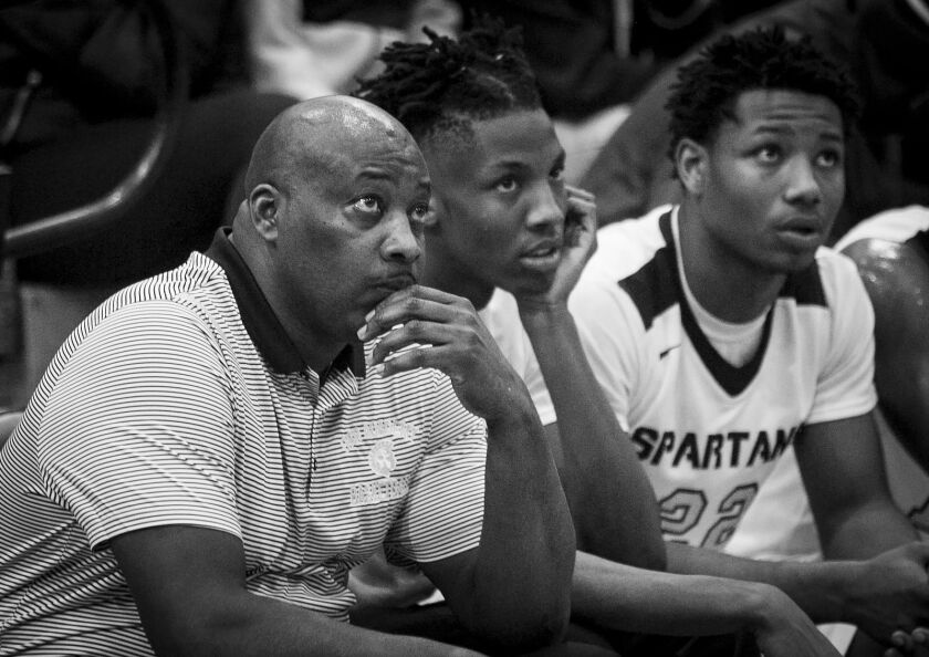 Coach Lou Adams, seated next to Tyron Mosley, watches from the bench as his team beats Westinghouse College Prep 58 – 55 at Orr Academy High School, Jan. 11, 2017.