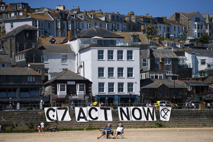Extinction Rebellion environmental activists attach a banner calling on G7 leaders to act on climate change on the beach in St Ives, Cornwall during the G7 summit on Sunday.