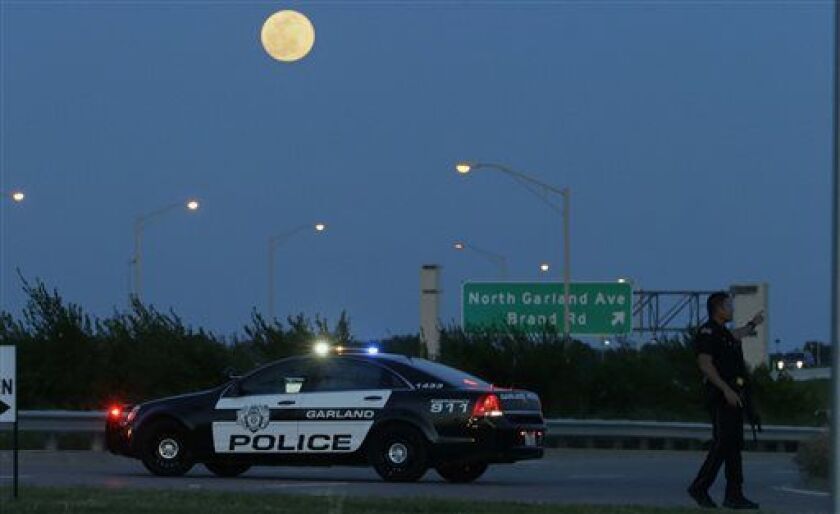 <small><strong>An armed police officer stands guard on a road near the Curtis Culwell Center in Garland, Texas. | LM Otero/AP</strong></small>